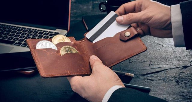 mão tirando cartão de carteira contendo criptomoedas e Bitcoin