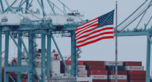 Uma bandeira dos EUA tremula próxima a contêineres de carga enquanto um navio é descarregado no Porto de Los Angeles, em San Pedro, Califórnia, EUA, em 1º de maio de 2025. REUTERS/Mike Blake