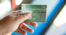 Mão segurando uma Carteira Nacional de Habilitação (CNH) em primeiro plano.