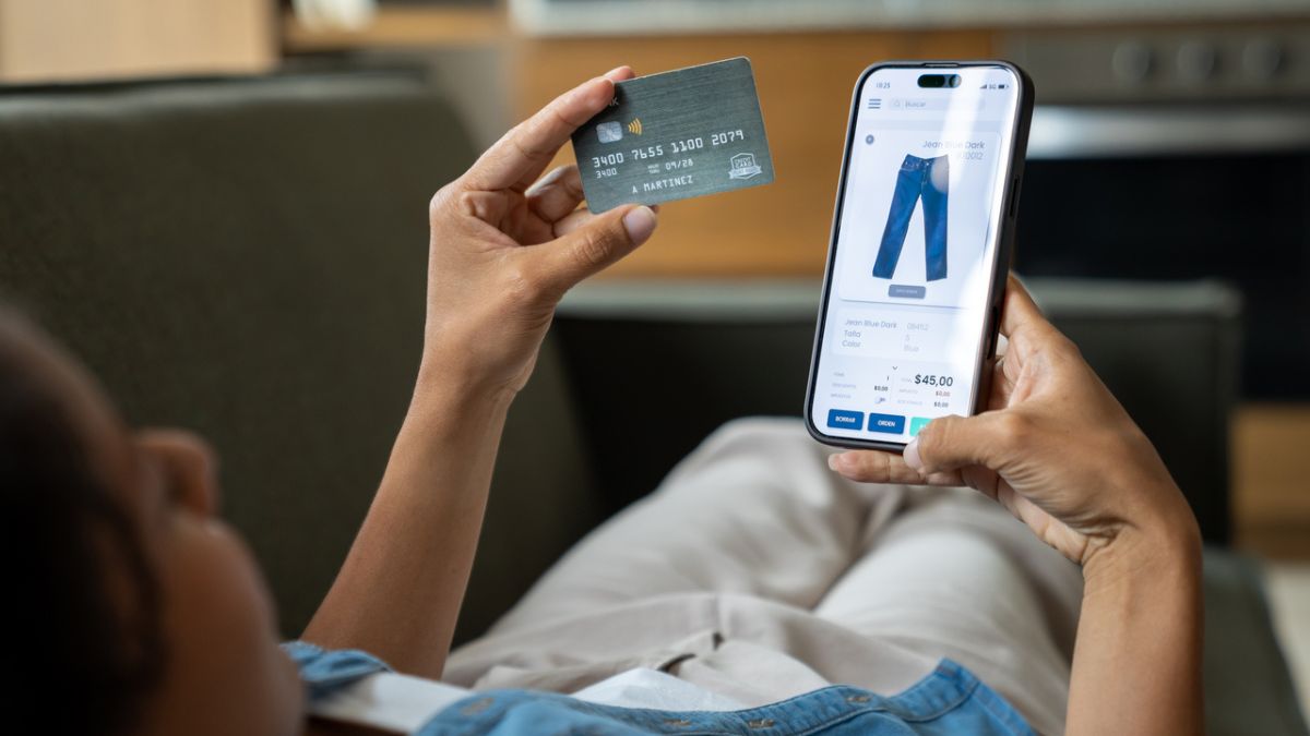 Mulher em casa comprando roupas on-line usando um aplicativo móvel e pagando com cartão de crédito