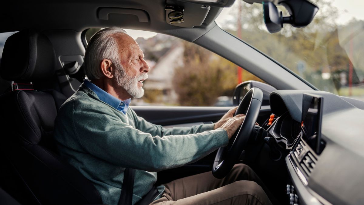 Vista lateral do homem sênior sério buzinando no trânsito.