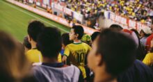 Fã do brasil usando uma camisa do Neymar e assistindo ao jogo no estádio.