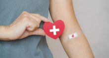 Mão humana sênior segurando forma de coração de papel vermelho e símbolo de gota de sangue vermelho em curativo para doação mundial de sangue e dia do doador e salvar conceito de vida ID da foto:1335544846