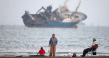 Pessoas se reúnem em uma praia, enquanto um navio no Estreito de Ormuz é visível, perto da praia de Bandar Abbas, no Irã, em 31 de maio de 2026. Amirhosein Khorgooi/ISNA/WANA (Agência de Notícias da Ásia Ocidental) via REUTERS