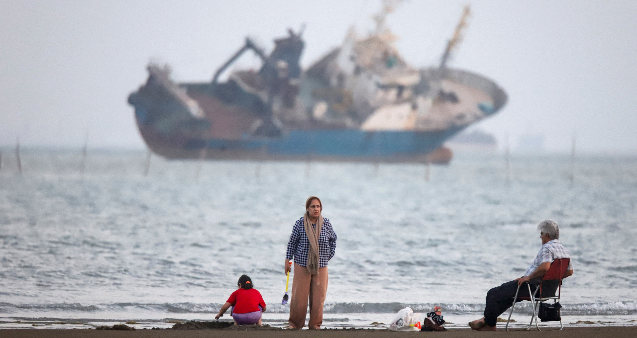 Pessoas se reúnem em uma praia, enquanto um navio no Estreito de Ormuz é visível, perto da praia de Bandar Abbas, no Irã, em 31 de maio de 2026. Amirhosein Khorgooi/ISNA/WANA (Agência de Notícias da Ásia Ocidental) via REUTERS