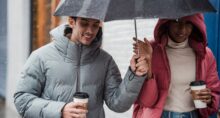 duas pessoas com roupas de frio segurando bebida quente e um guarda chuva