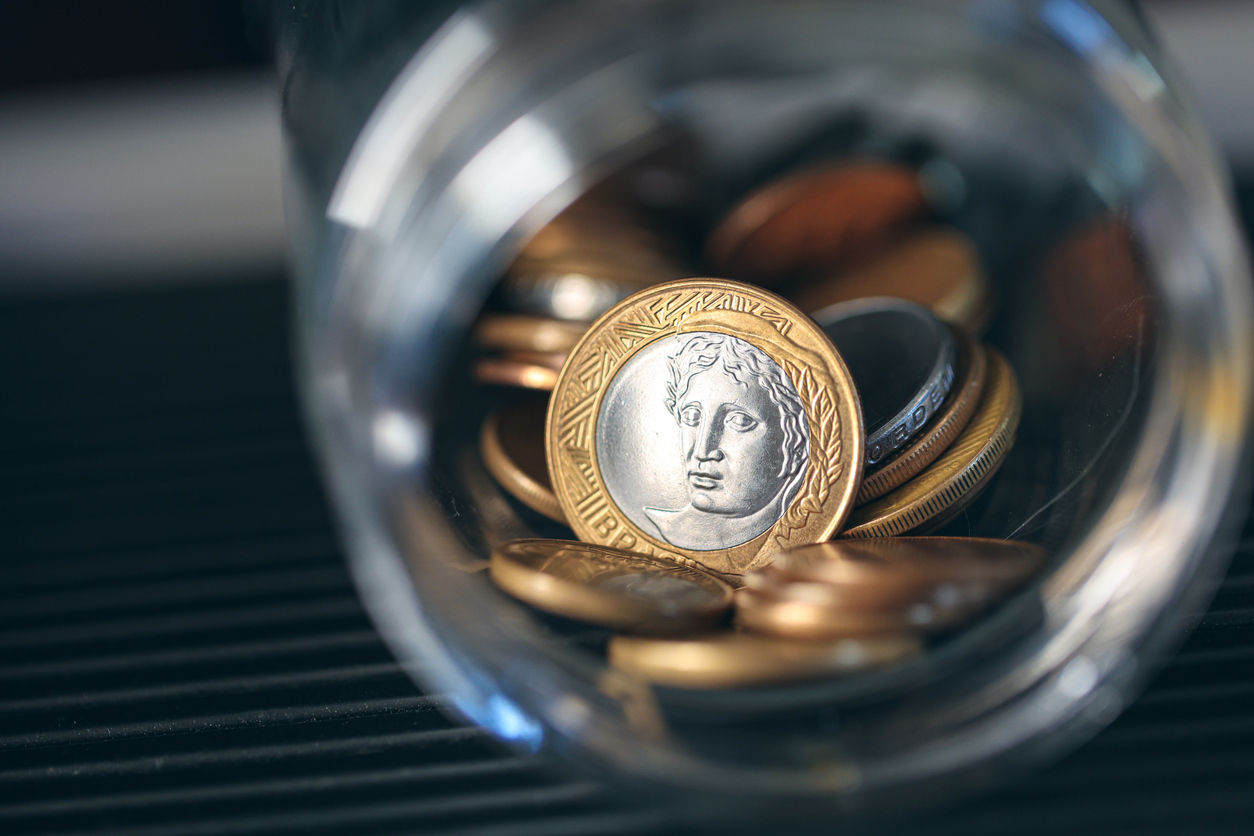 Real, Money from Brazil. Brazilian coins inside a glass jar. Highlight for 1 Real coin. Brazilian economy. Dark environment. Macro photography.