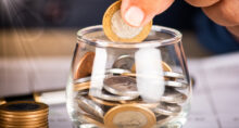 Businessman holding coins and putting into glass pot. Saving concept for financial accounting.