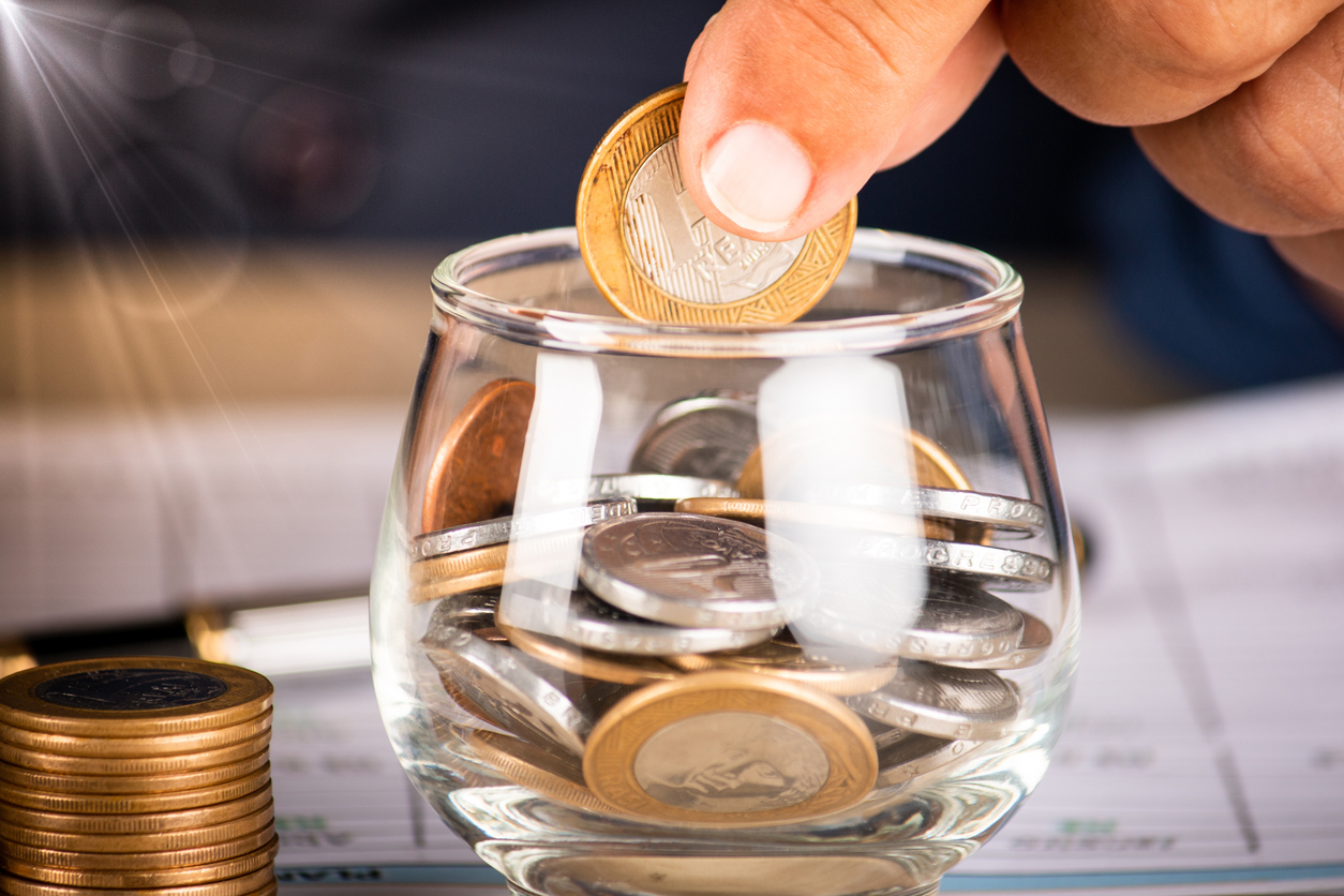 Businessman holding coins and putting into glass pot. Saving concept for financial accounting.